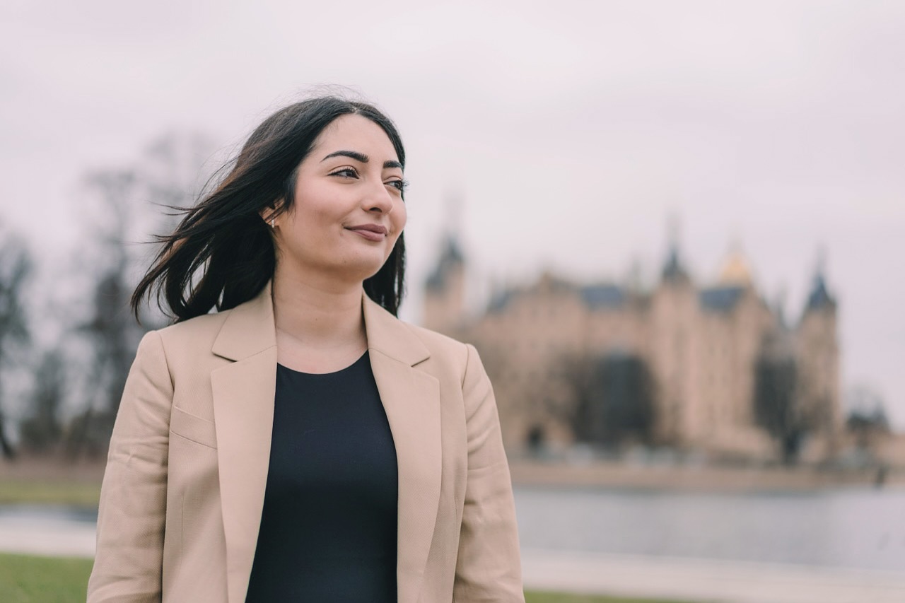 Portrait von Reem Alabali-Radovan mit dem Schweriner Schloss im Hintergrund.